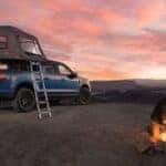 A blue 2025 Ford F-150 is shown parked on a campsite.