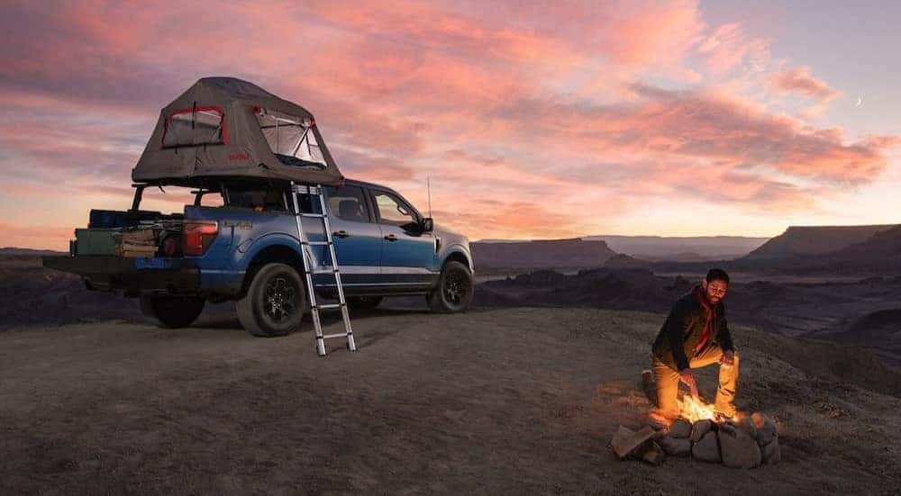 A blue 2025 Ford F-150 is shown parked on a campsite.