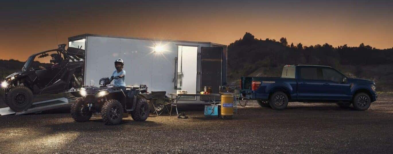 A blue 2025 Ford F-150 Tremor is shown parked while towing a trailer.