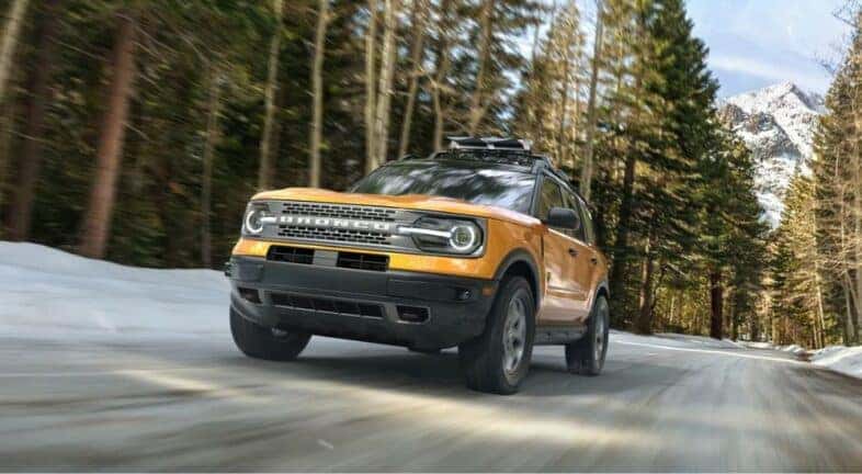 A yellow 2023 Ford Bronco Sport is shown driving near a mountain.