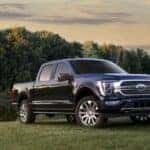 A blue 2023 used Ford F-150 for sale near Schenectady is shown parked near a pond.