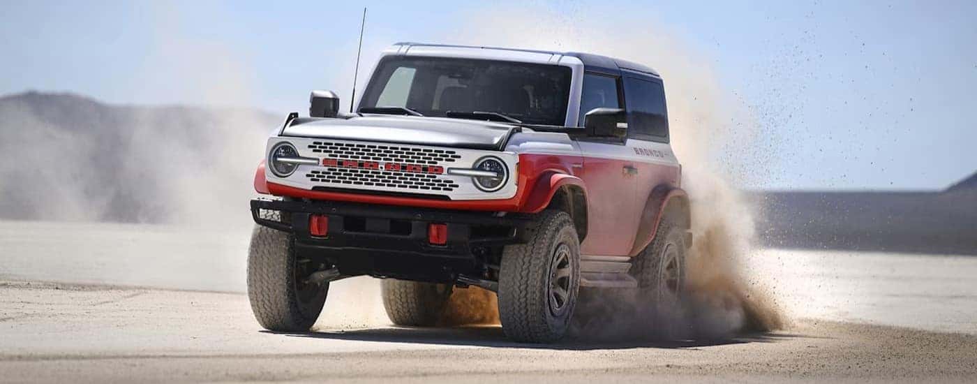 A red and white 2025 Ford Bronco Stroppe is shown driving off-road.