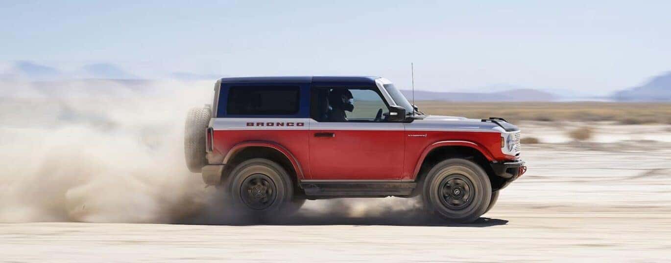 A red 2025 Ford Bronco Stroppe Edition is shown driving off-road.