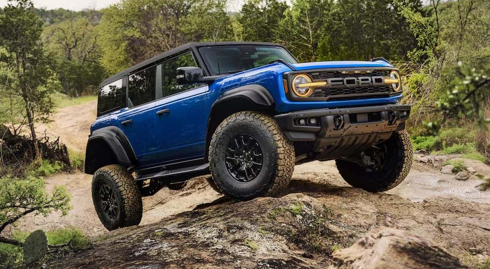 A blue 2025 Ford Bronco Raptor off-roading during a 2025 Ford Bronco vs 2025 Jeep Wrangler comparison.