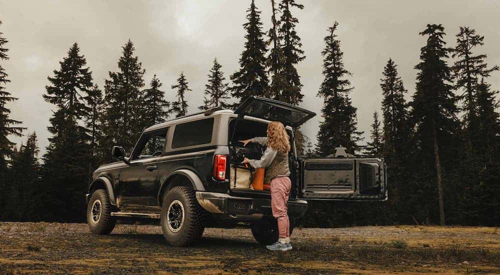 A woman is getting camping gear out of the back of a black 2025 Ford Bronco Sasquatch.