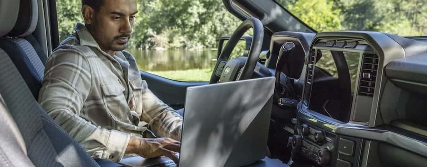 A person is shown using a laptop in a 2025 Ford F-150 XLT.