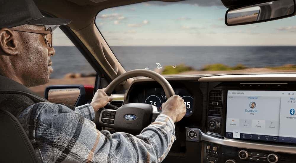 A man is driving in a 2025 Ford F-150 King Ranch during a 2025 Ford F-150 vs 2025 Ram 1500 comparison.