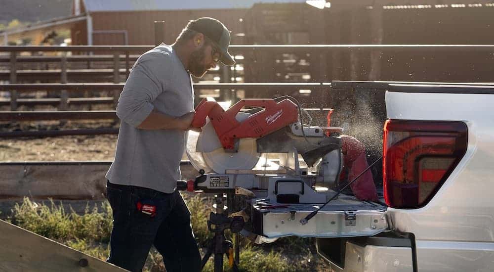 A man is cutting wood on the bed of a 2025 Ford F-150.