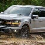 A silver 2025 Ford F-150 Tremor off-roading on dirt.