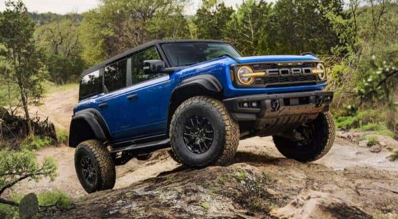 A blue 2025 Ford Bronco Raptor is shown off-roading.