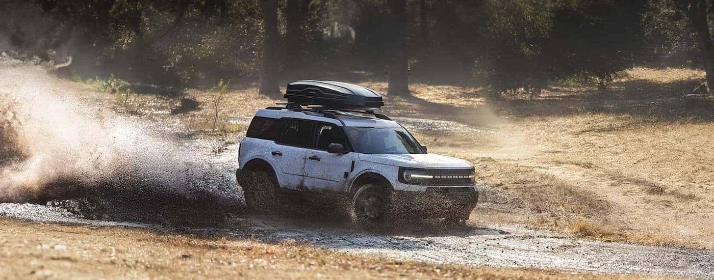 A white 2025 Ford Bronco Sport off-roading in mud.