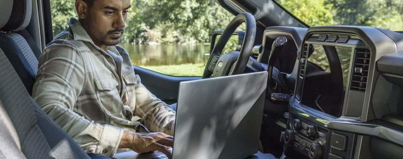 A person using a laptop inside of a 2025 Ford F-150.