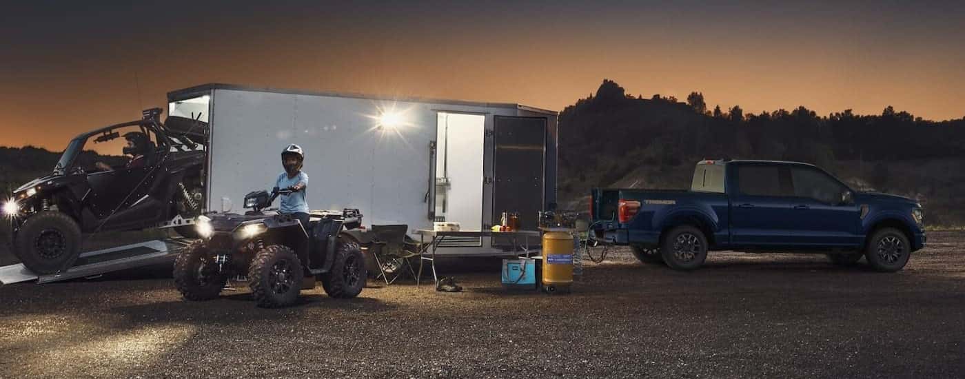 A blue 2025 Ford F-150 Tremor parked while towing a trailer.