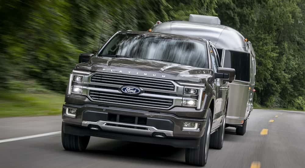 A black 2025 Ford F-150 Platinum Plus towing a camper.