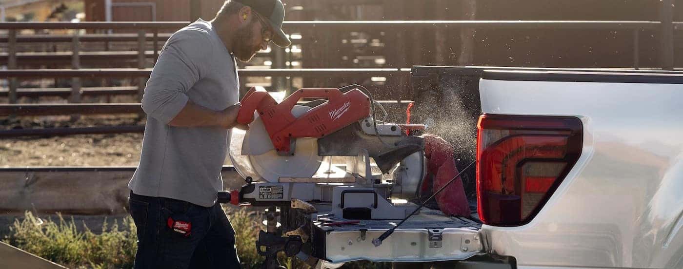 A person using a saw on the open tailgate of a 2025 Ford F-150.