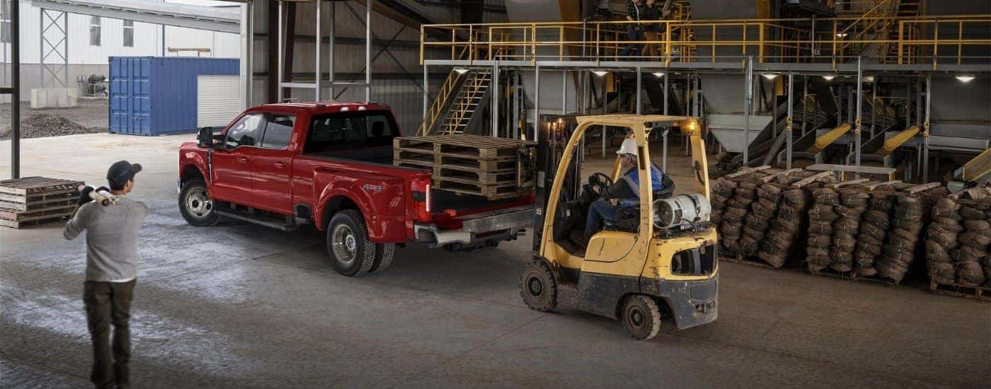 A forklift is loading pallets on a red 2025 Ford F-350 Lariat.