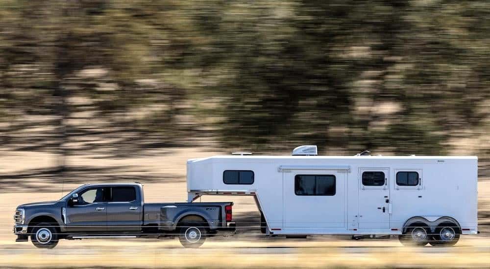 A grey 2025 Ford F-350 is shown from the side while towing a camper.