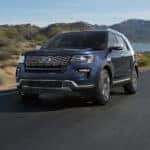 A used dark blue 2018 Ford Explorer for sale near Troy driving by a lake.