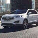 A used white 2024 Ford Edge for sale in Albany driving in a city.