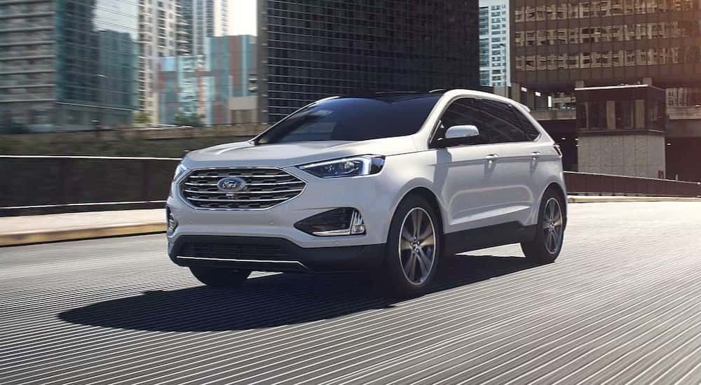 A used white 2024 Ford Edge for sale in Albany driving in a city.