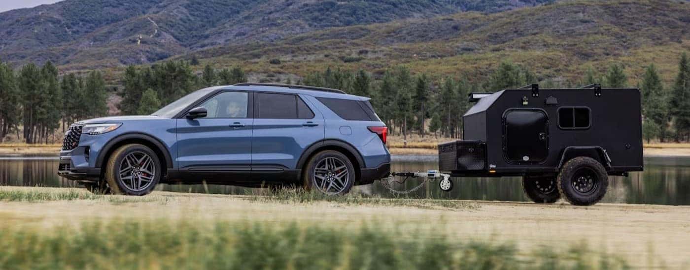 A blue 2025 Ford Explorer ST towing a trailer off-road.