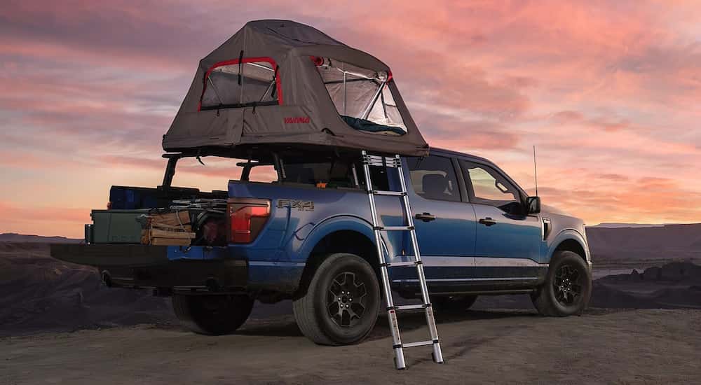 Rear of a blue 2025 Ford F-150 STX with a tent and open tailgate.