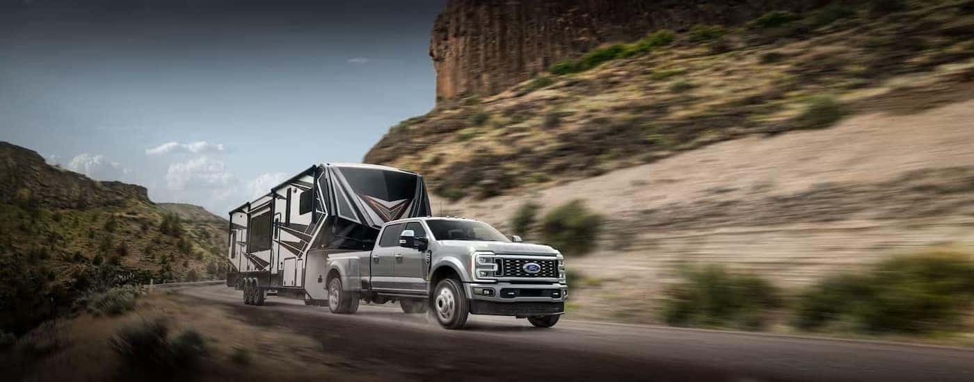 A silver used Ford F-350 for sale is towing a trailer on a highway.