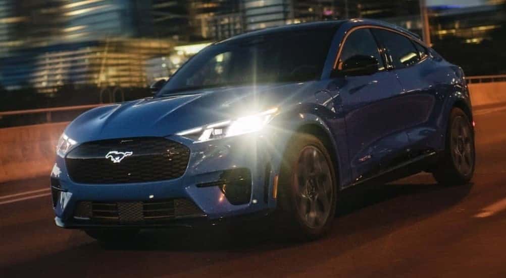 A blue 2025 Ford Mustang Mach-E GT driving at night.