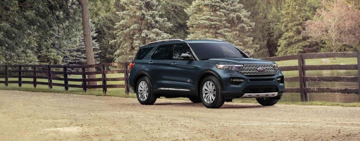 Dark blue 2023 Ford Explorer King Ranch driving by a fence.