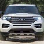 A white 2023 Ford Explorer King Ranch driving on a dirt road.