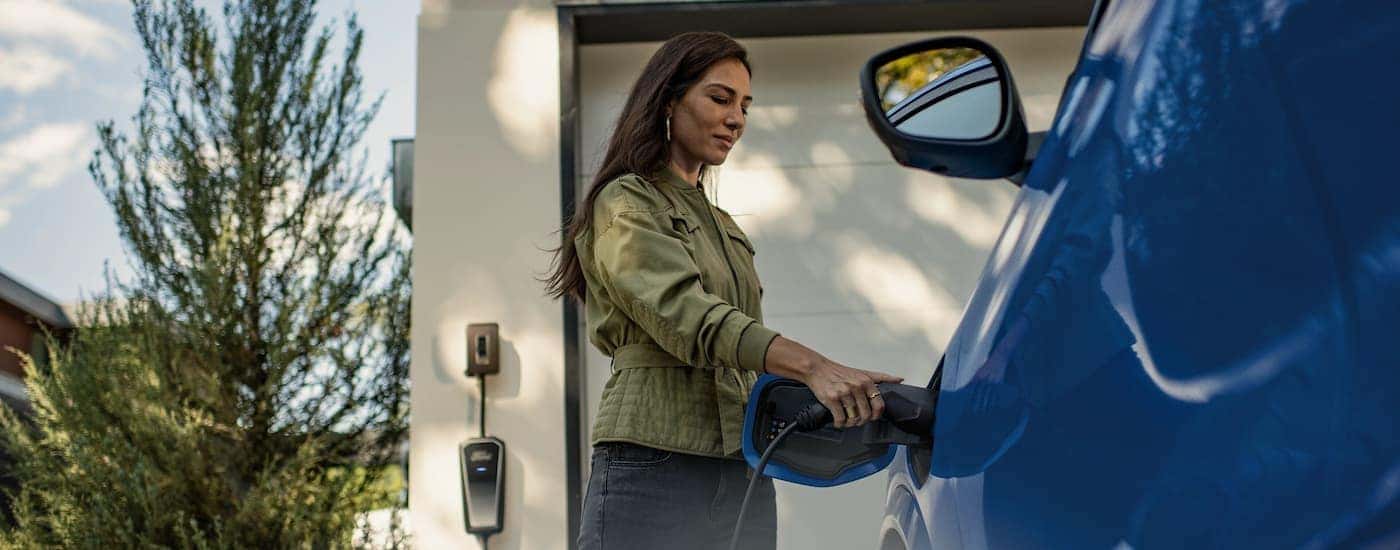 A woman charging a blue 2025 Ford Mustang Mach-E