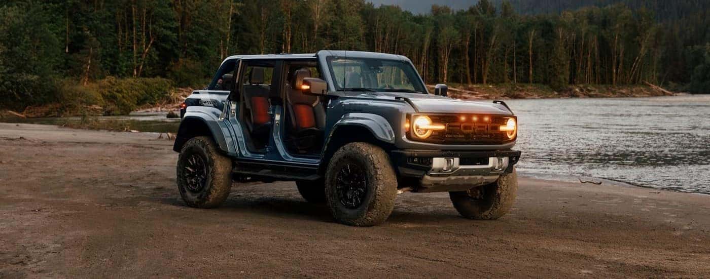 A blue 2025 Ford Bronco Raptor parked near a lake.