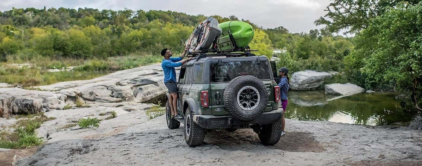 A green 2025 Ford Bronco parked with kayaks on the roof.