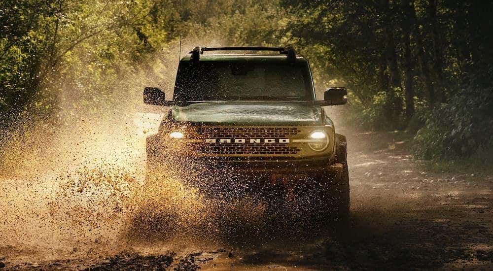 A green 2025 Ford Bronco off-roading in mud