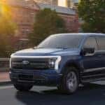 A blue 2025 Ford F-150 Lightning driving on a city street.