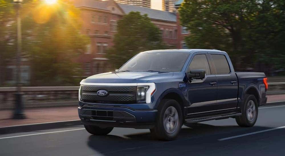 A blue 2025 Ford F-150 Lightning driving on a city street.