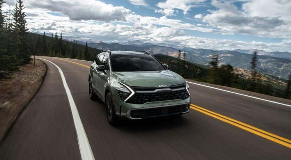Green 2023 Kia Sportage driving down winding roads.