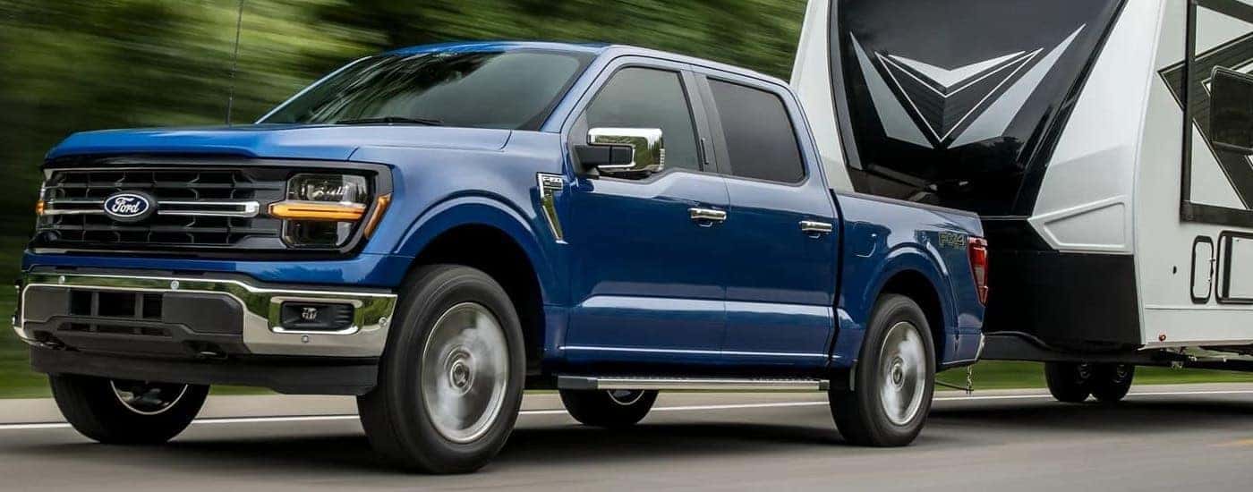 Blue 2024 Ford F-150 XLT towing a camper