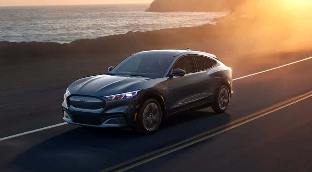 A gray 2021 Ford Mustang Mach-E driving on a highway.