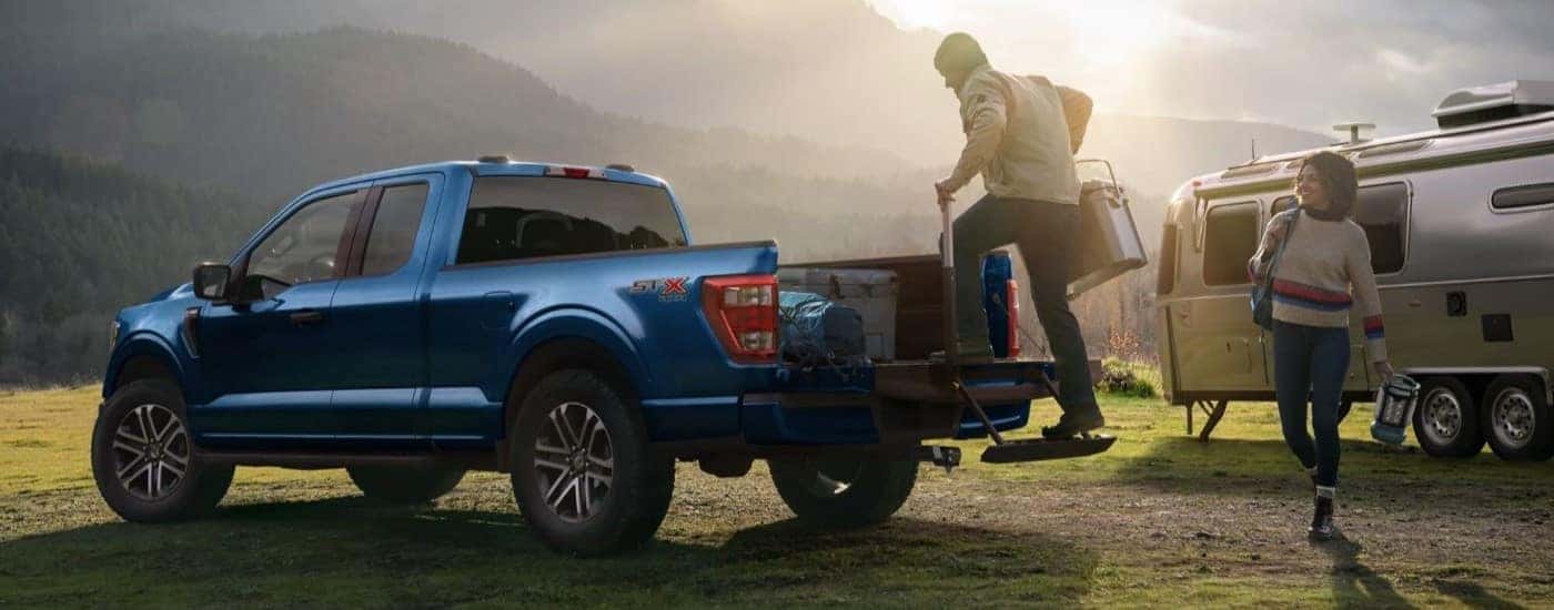 A blue 2025 Ford F-150 STX parked at a campsite
