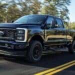 A black 2025 Ford F-250 XL STX driving down a highway