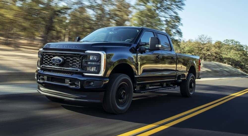 A black 2025 Ford F-250 XL STX driving down a highway