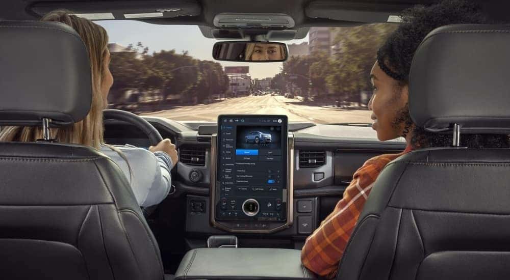 Two women driving and discussing the 2025 Ford F-150 Lightning vs 2025 Tesla Cybertruck