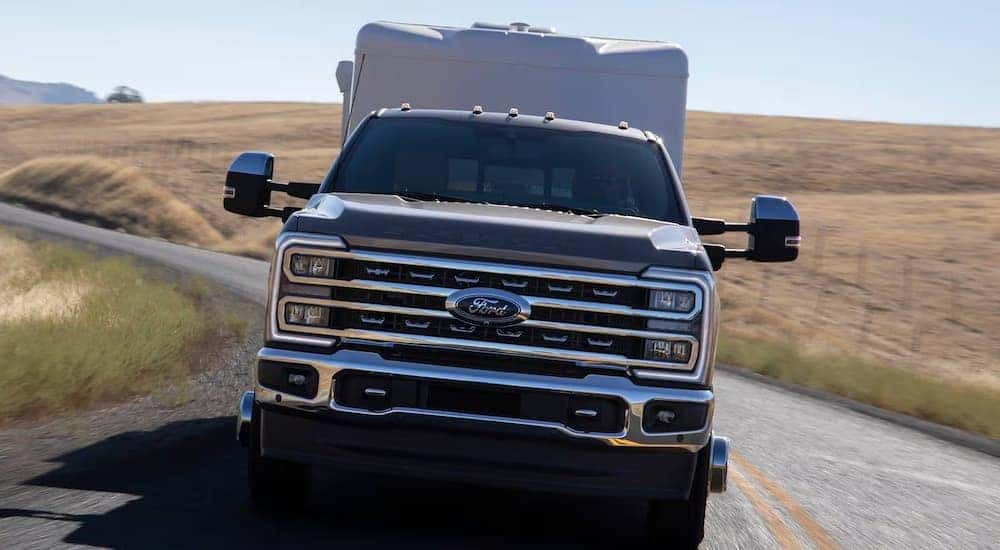 A black 2025 Ford F-350 towing a camper behind
