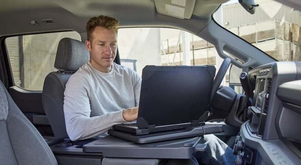 A person using a laptop in a 2025 Ford F-350.