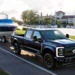 A black 2025 Ford F-350 towing a boat.
