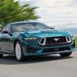 A blue 2026 Ford Mustang driving down a street