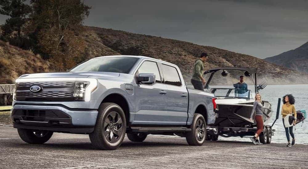 A silver 2023 Ford F-150 Lightning towing a boat.