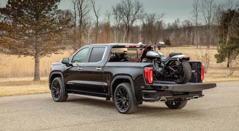 Black 2020 GMC Sierra 1500 from the back with a motorcycle in the bed.