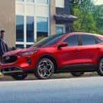 Two people walking up to a red 2025 Ford Escape from the side.